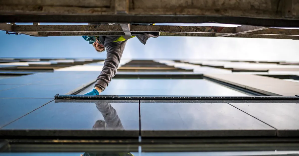 A glazier fitting a glass panel on a building facade