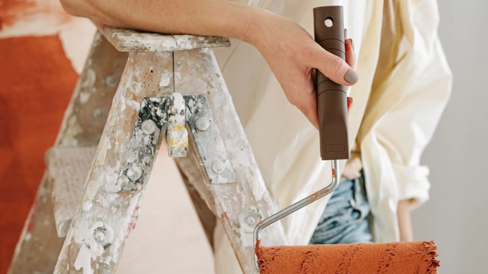 Painter with a roller beside a spattered step ladder